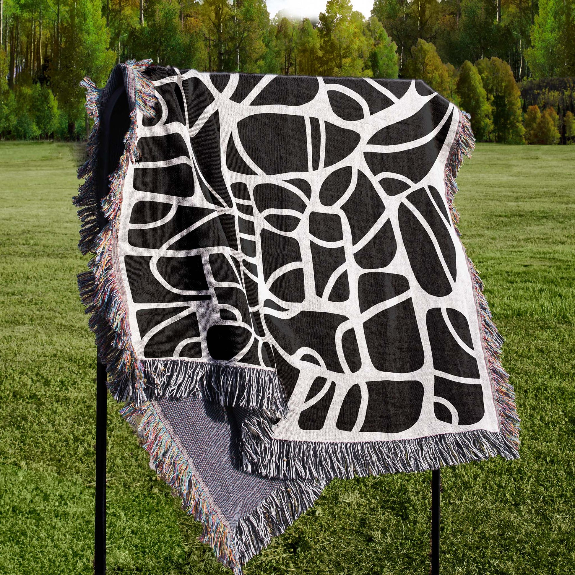 Woven blanket with an abstract design draped over a stand