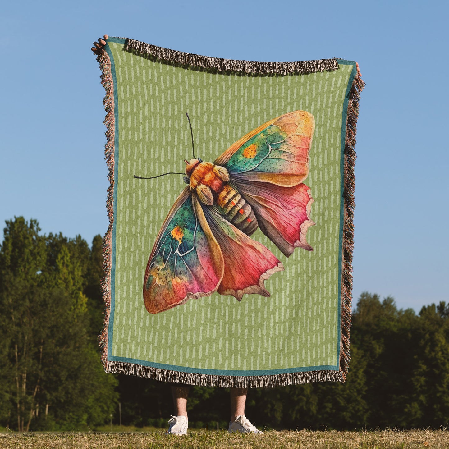 a woman holding up a woven blanket with a moth design